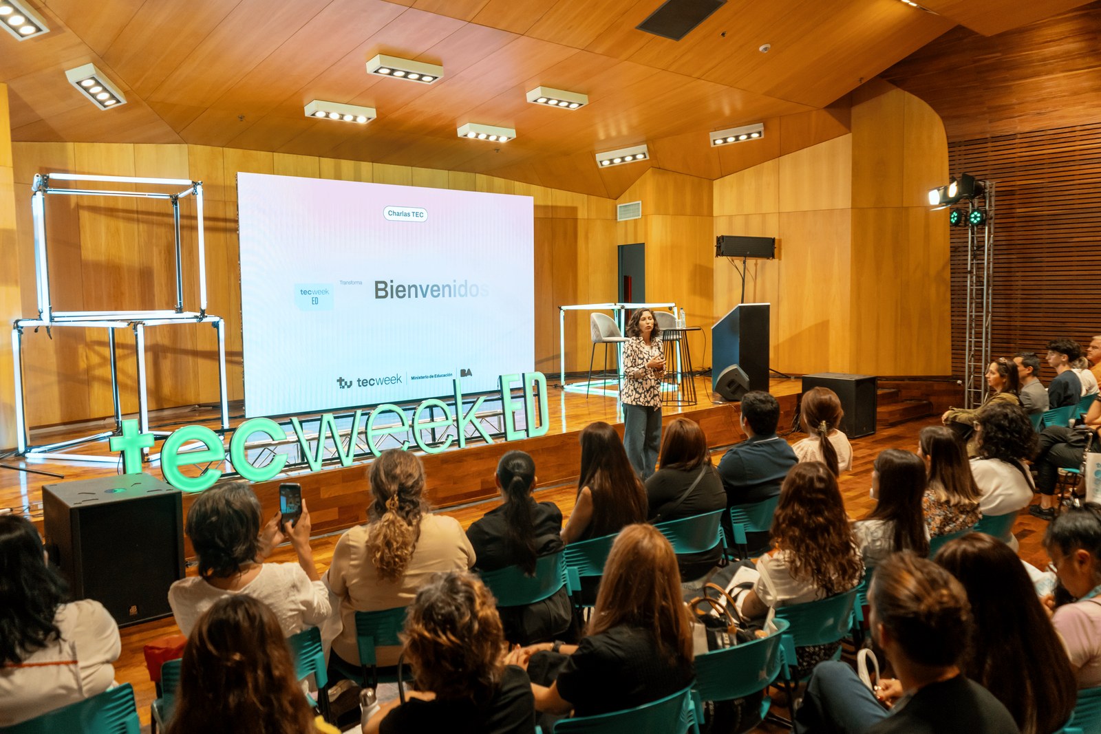 Orador presentando sobre inteligencia artificial en el escenario principal, con el público en primer plano